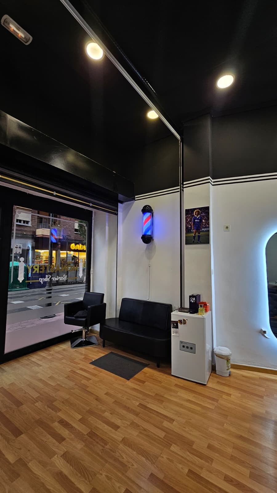 Zona de espera con sofá y polo de barbería